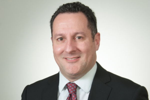 Dr. Photo of Kenneth Nusbacher in black suit jacket, white shirt, and red tie. 