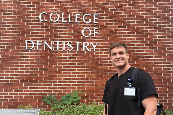 Photo of Joshua Howells in front of UK College of Dentistry sign.