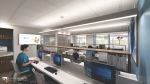 Modern dental workroom with accessible desks and computer stations. Staff members work at ergonomic chairs under bright lighting, with wide pathways and organized storage throughout the space.