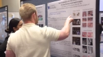 Student explains poster research to another student.