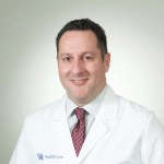 Dr. Kenneth Nusbacher in white coat, red tie, and pale blue shirt.