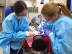 Two female students working on a patient in mobile clinic.