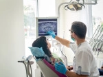 Dentist pointing to a dental x-ray while patient looks on from a dental chair.