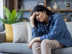 Woman sitting on a couch experiencing a migraine.