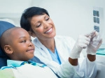 Pediatric patient and dentist look at x-rays together.