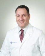 Dr. Kenneth Nusbacher in white coat, red tie, and pale blue shirt.